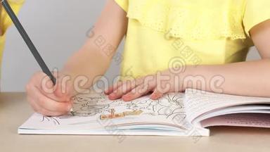 一个女孩画一本彩色书。 一个小女孩的特写`她的手拿着铅笔画画。